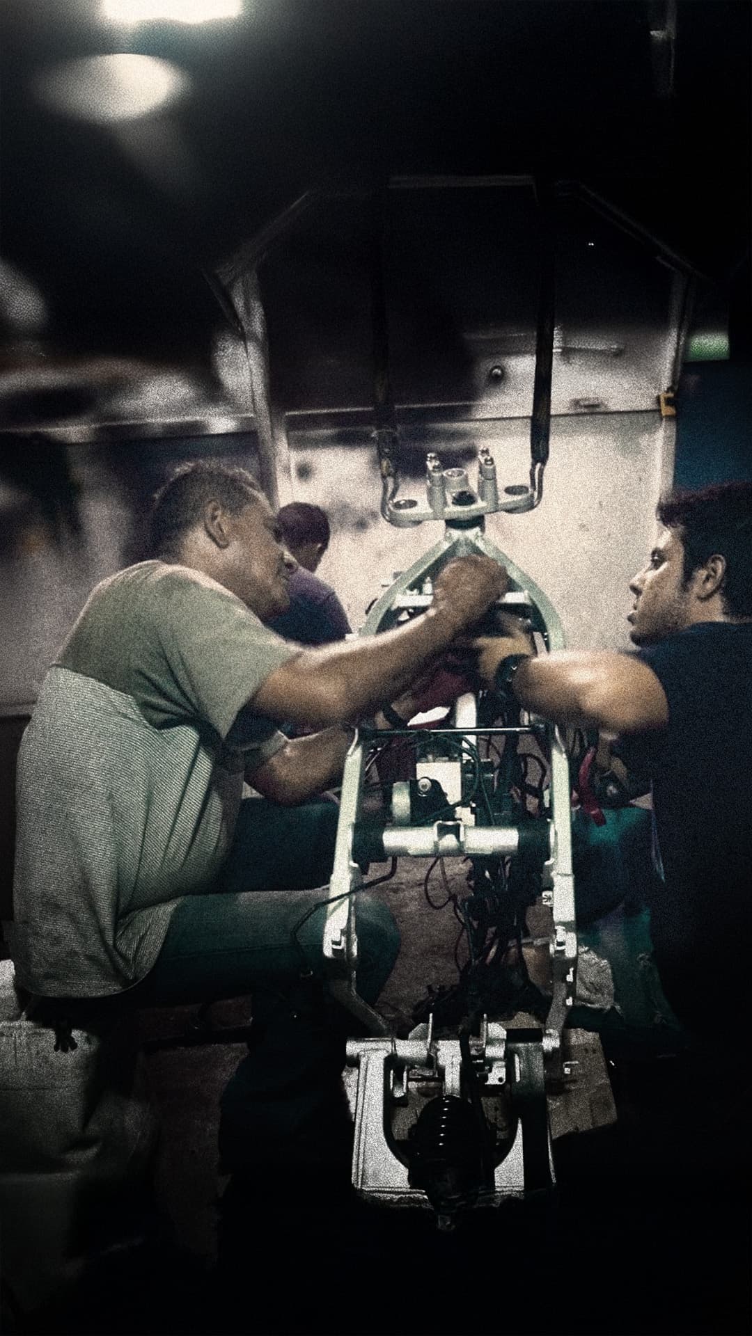 Enzo Polini and his father working on a motorcycle frame in the workshop.